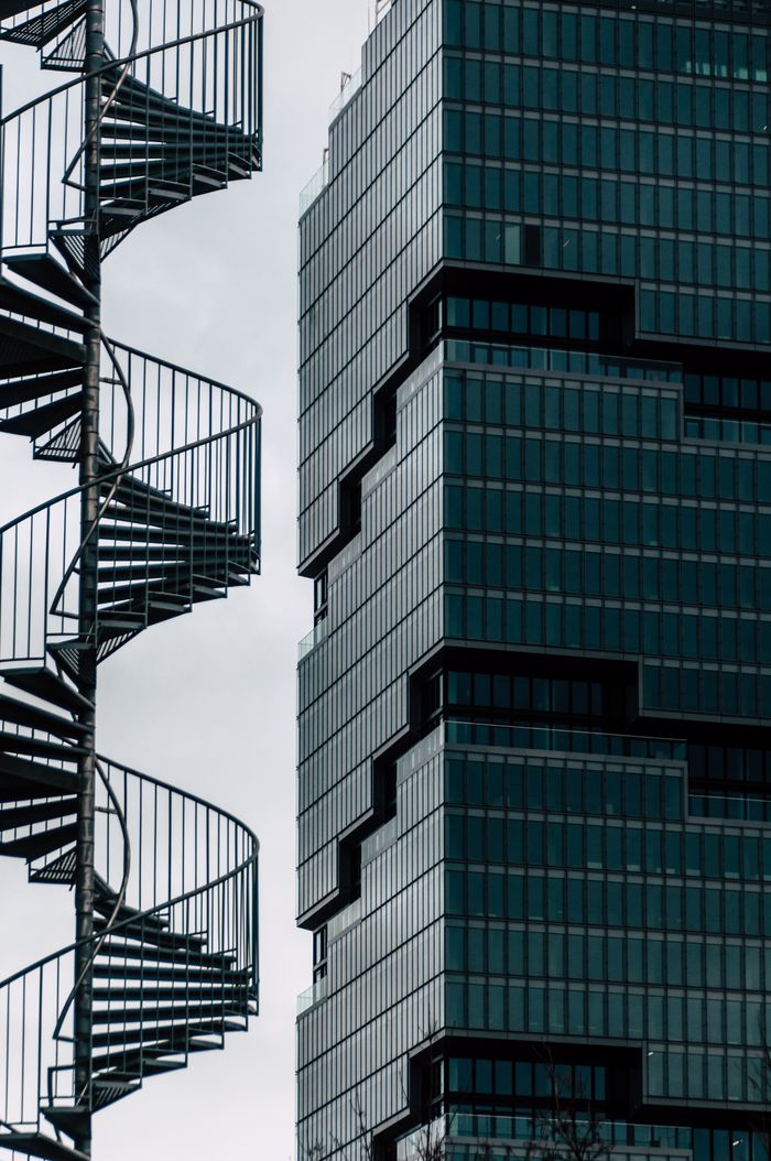 Striking contrast between spiral staircases and modern glass skyscraper facade.